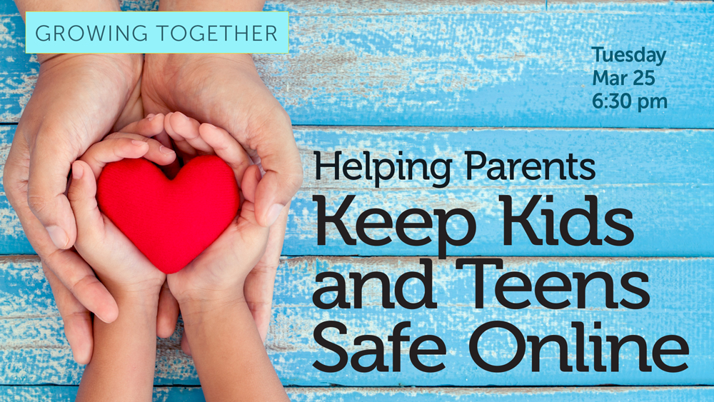 adult hands cradling child's hands holding a heart against a blue wooden table background