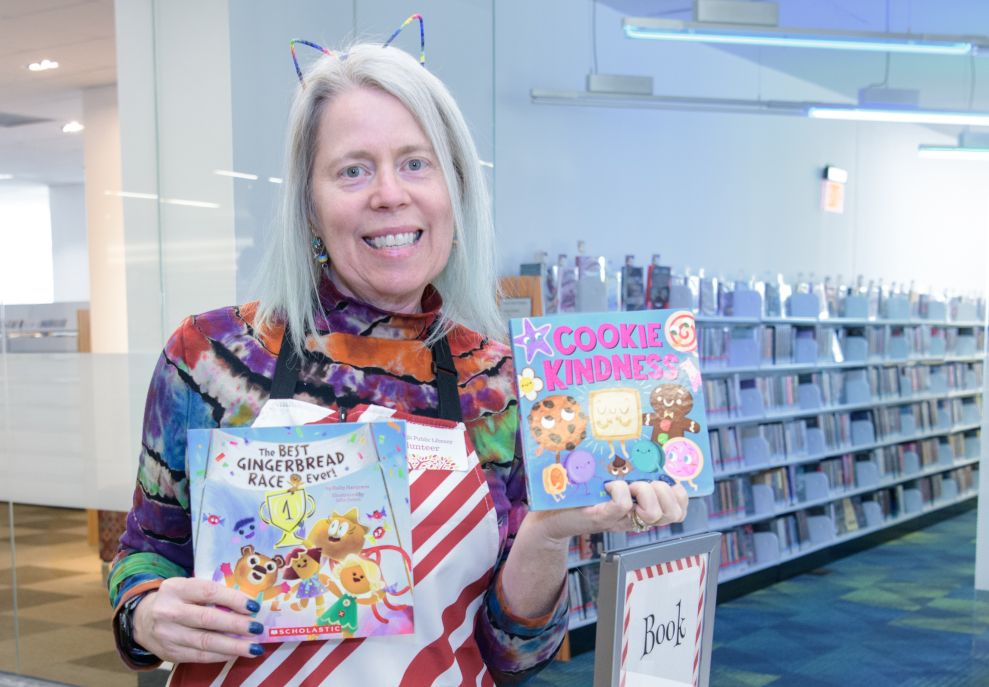 Woman wearing a cat ear headband holds books and smiles