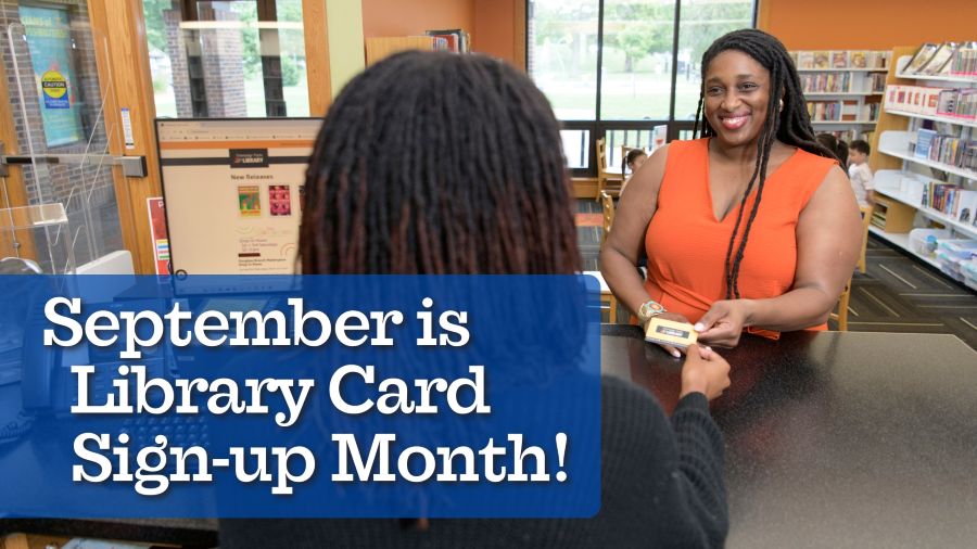 A woman recieves a library card and smiles.