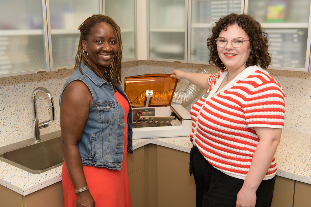 A customer and librarian stand together at a Glowforge machine and smile